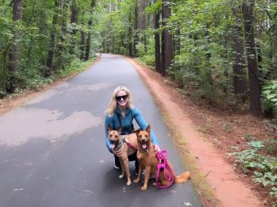 Lauren Buglioli is with her dogs on the road in the middle of the woods.